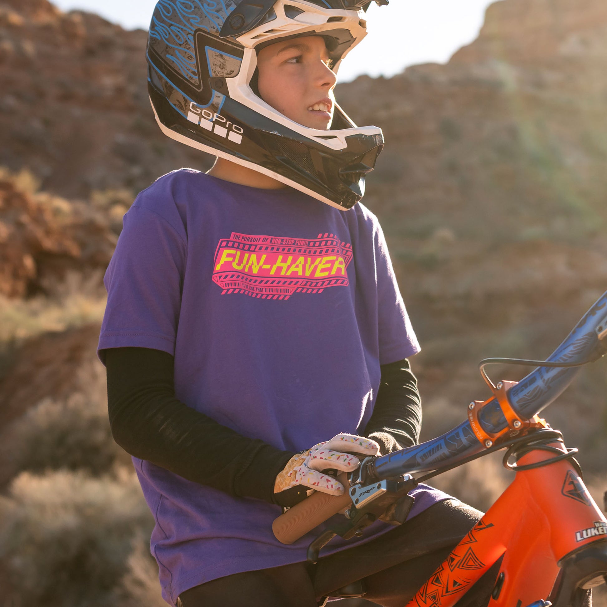 Future lifelong Fun-Haver wearing the Fun-Haver Purple Rush Pursuit Youth T-Shirt with Magenta and Yellow Fun-Haver logo graphics out in the desert in pursuit of fun