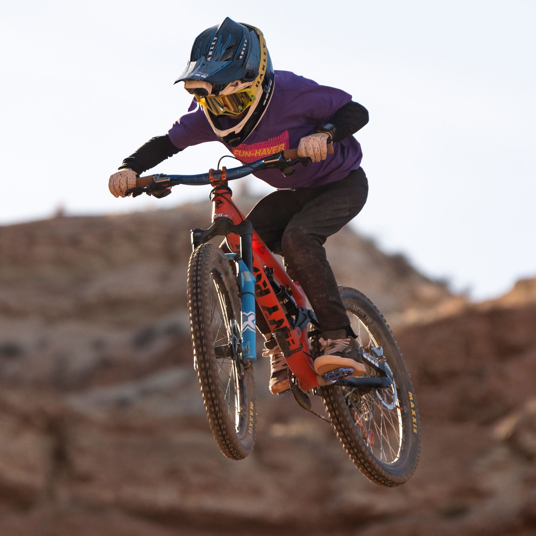 Future lifelong Fun-Haver wearing the Fun-Haver Purple Rush Pursuit Youth T-Shirt with Magenta and Yellow Fun-Haver logo graphics in 2 wheel action in the air