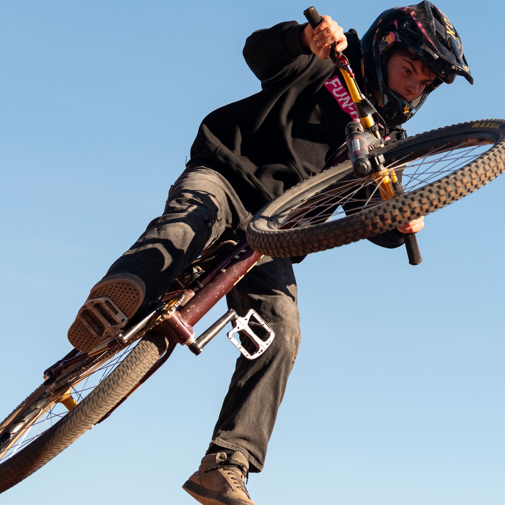 Cam wearing the Black Fun-Haver Energy Pullover Hoodie catching some air on two wheels.