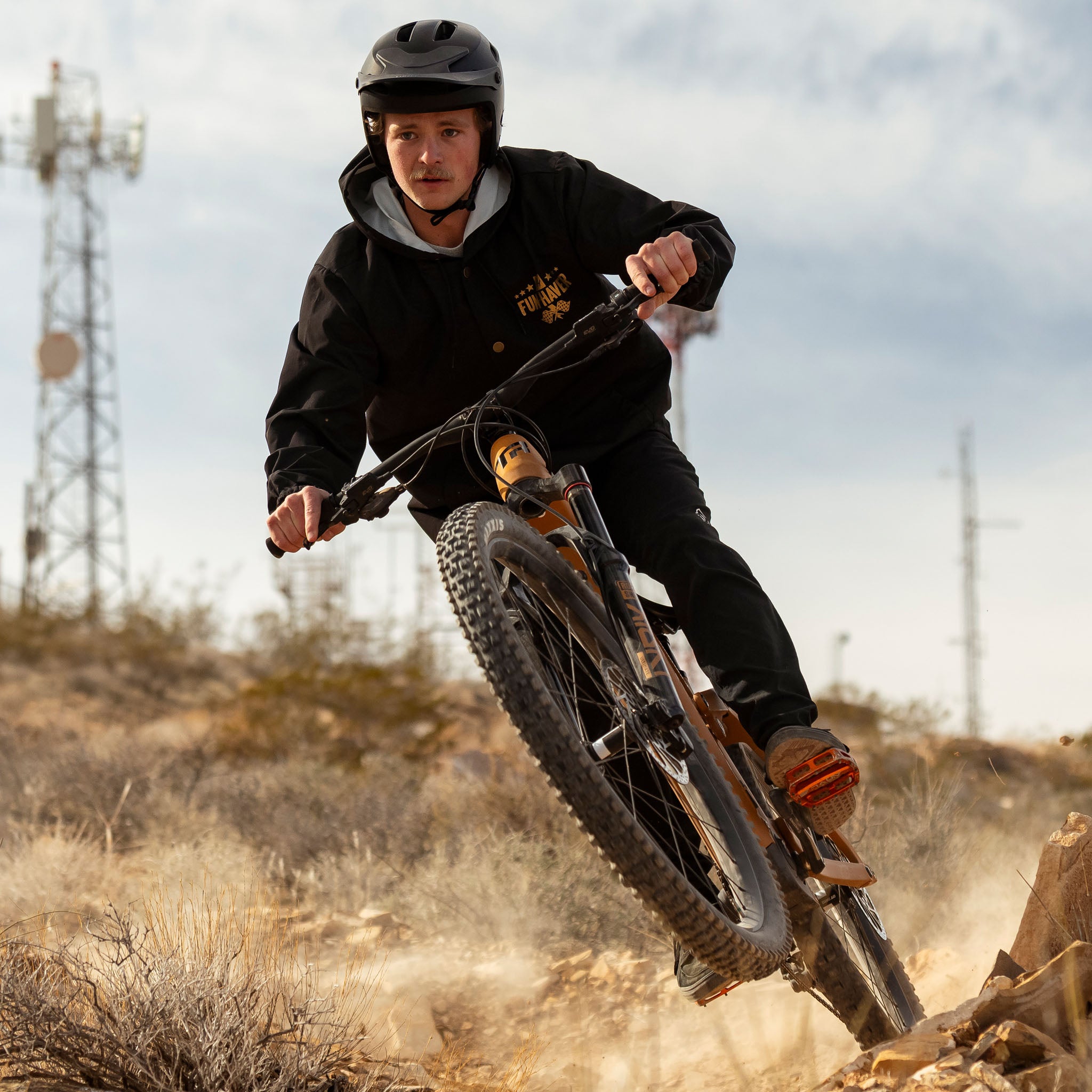 Joel riding his mountain bike while wearing the Black Full Time Fun-Haver® Winbreaker Coaches Jacket.