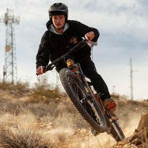 Joel riding his mountain bike while wearing the Black Full Time Fun-Haver® Winbreaker Coaches Jacket.