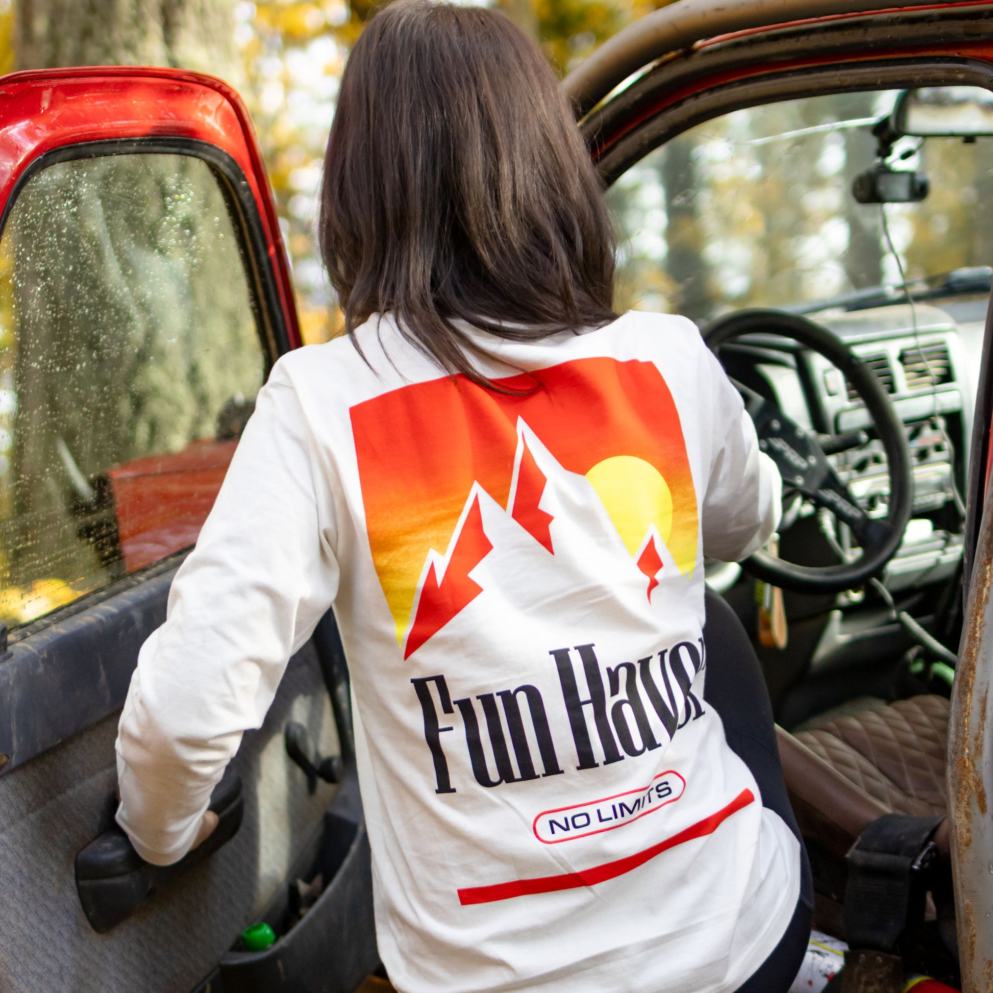 Back view of Kelsie Heck wearing the Fun-Haver No Limits White Long Sleeve T-Shirt, getting in her Toyota Tacoma truck.