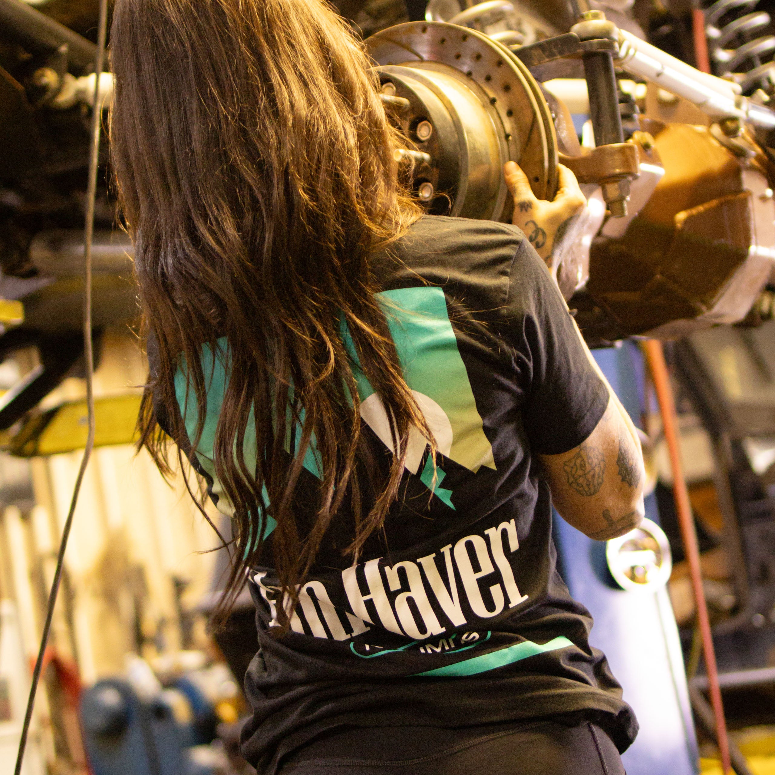 Back view of Kelsie Heck wearing the Fun-Haver No Limits Black T-Shirt while working on her truck.