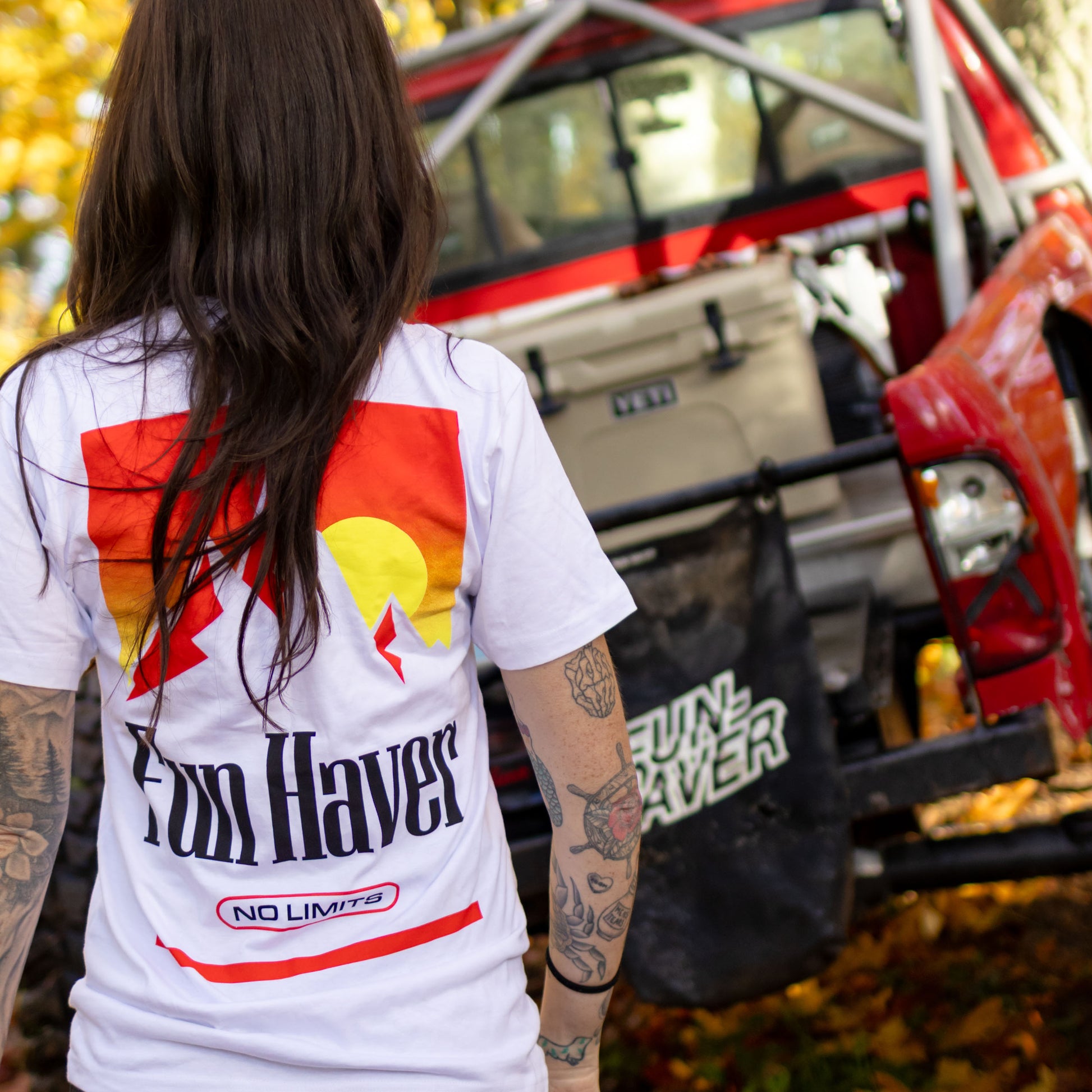 Back view of Kelsie Heck wearing the Fun-Haver No Limits White T-Shirt looking at her Toyota Tacoma.