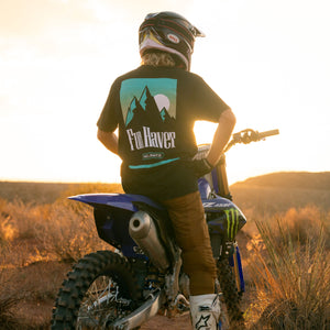 Motocross rider on his bike wearing the Fun-Haver No Limits Black T-Shirt looking at the Sunset in the desert.