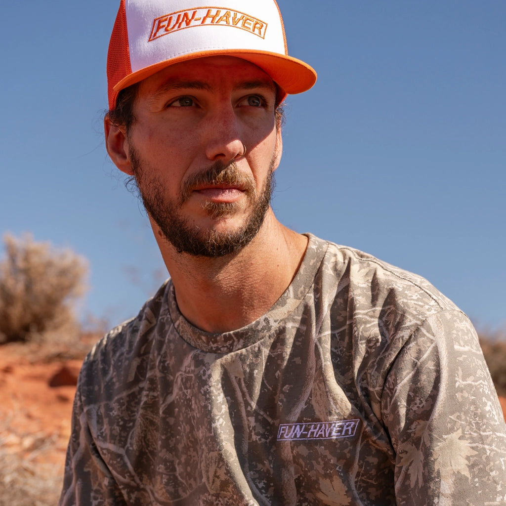 Fun haver wearing the Fun-Haver Long Sleeve Stealth Camo T-Shirt and Orange Decky Trucker Hat out in the desert.