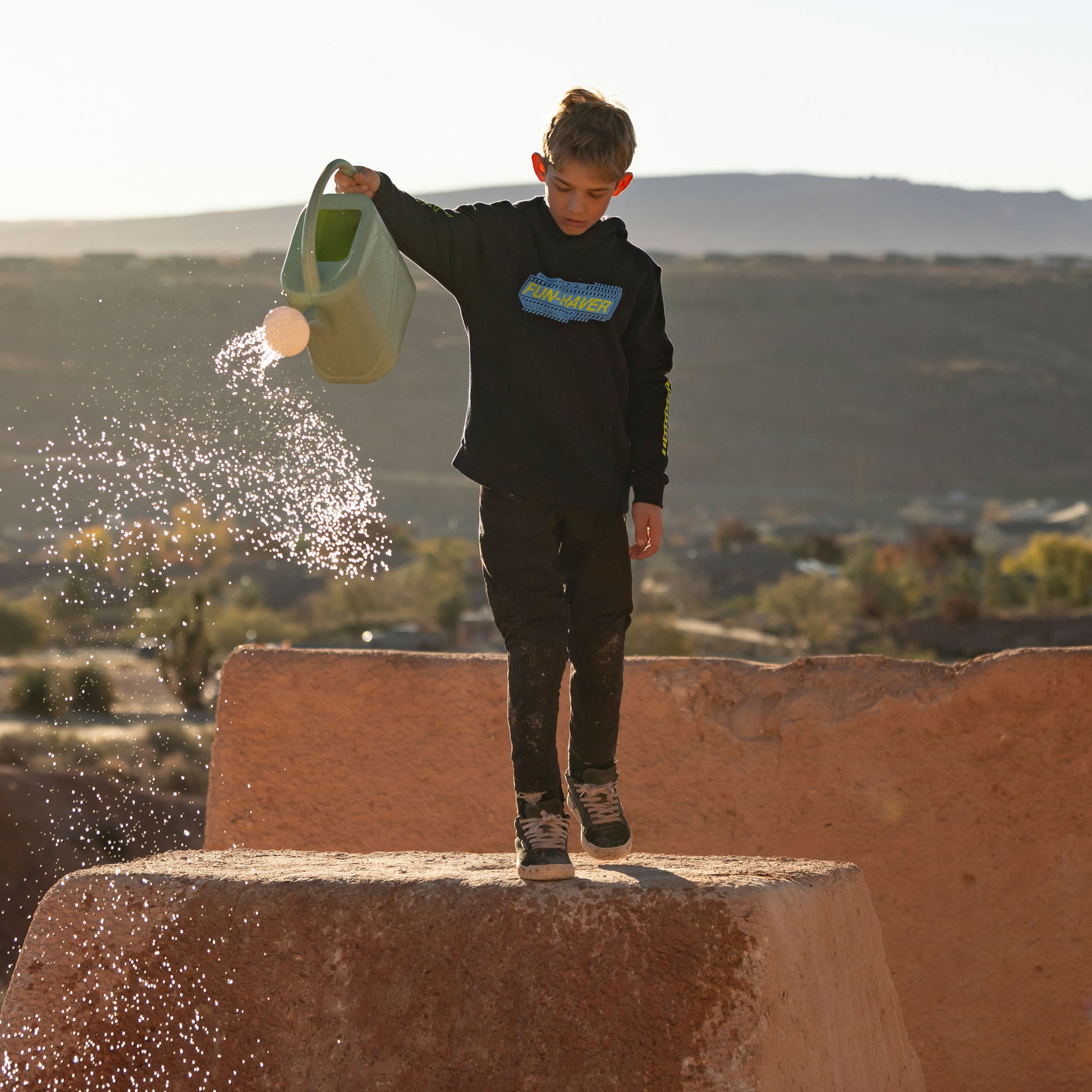Wes wearing the Fun-Haver Midnight Navy Pursuit Youth Pullover Hoodie while watering the track.
