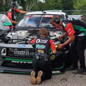 RTR Vehicles crew members wearing the James Deane 2026 RTR Drift Team Sublimated Shirts while wrenching on  James Deane's Ford Mustang RTR at a Formula Drift event.